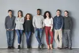 Group of youths standing against gray wall.