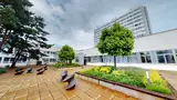 A young woman sitting on a bench in front of a building, enjoying a peaceful moment outdoors.