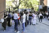 A queue of individuals patiently waiting outside a structure, forming a line, with no specific details provided