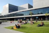 Group of people sitting on grass in front of university